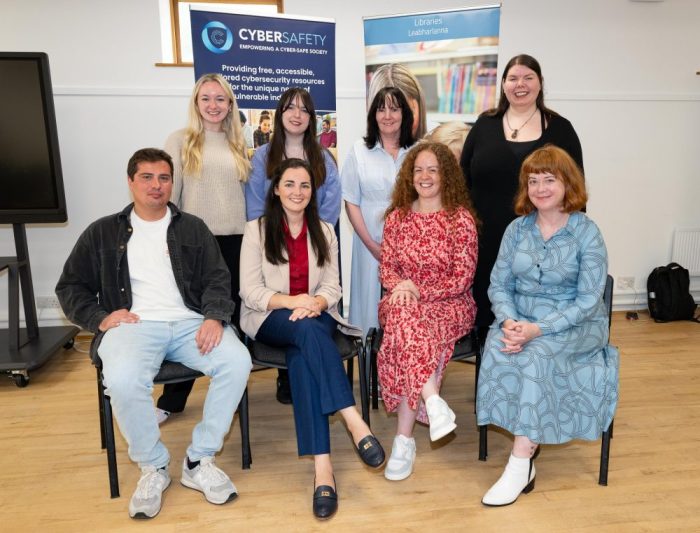 Photographed by Clive Wasson, EIght Cyber Safety team members sit smiling in front of a cyber safety banner. Pictured from the left are Elaine Calnan, Dr Ashley Sheil, co-PI Dr Michelle O' Keeffe, Jacob Camilleri, PI Dr Hazel Murray, Melanie Gruben, Anne-Ryan Duffy, and Moya Cronin.